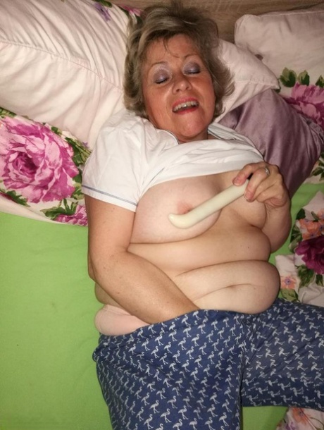 Horny older woman licks her nipple before dildoing her hairy pussy