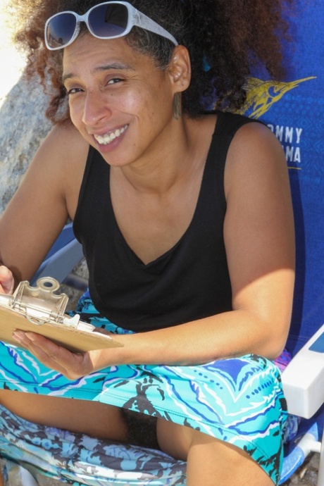 Mature ebony with hairy armpits Divine reveals her bushy cunt on the beach